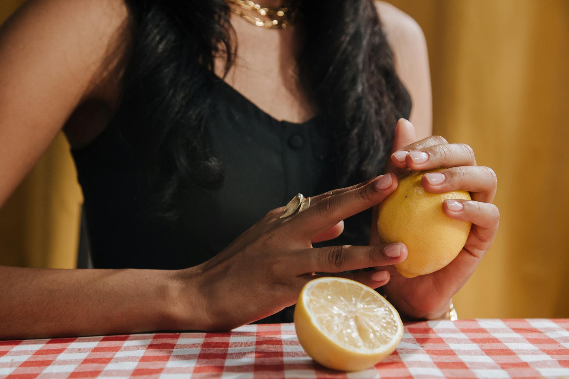 Woman holding a fresh lemon at a dining table, symbolizing vitality and natural wellness