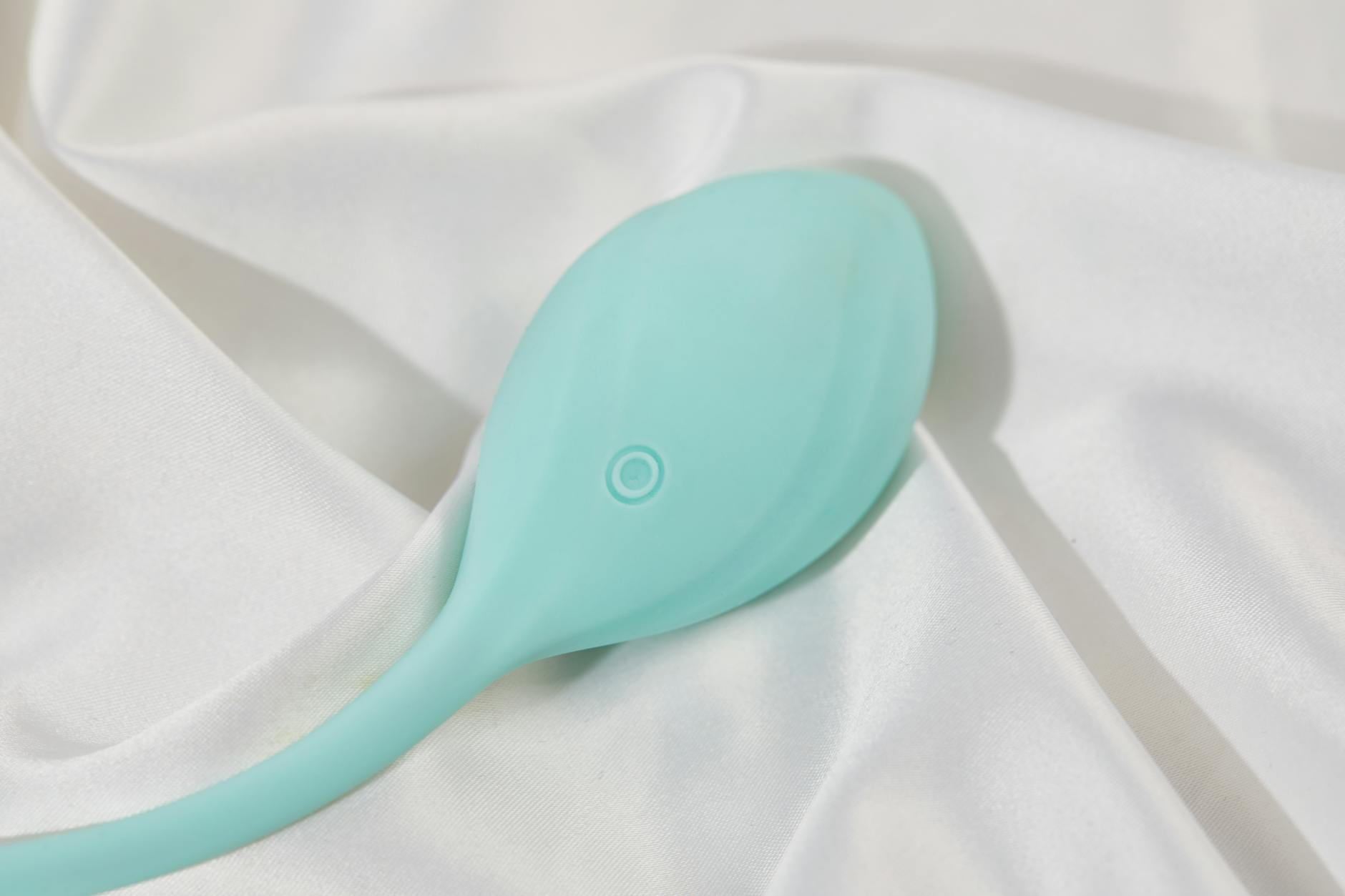 A blue silicone clitoral vibrator held in hand against a purple background