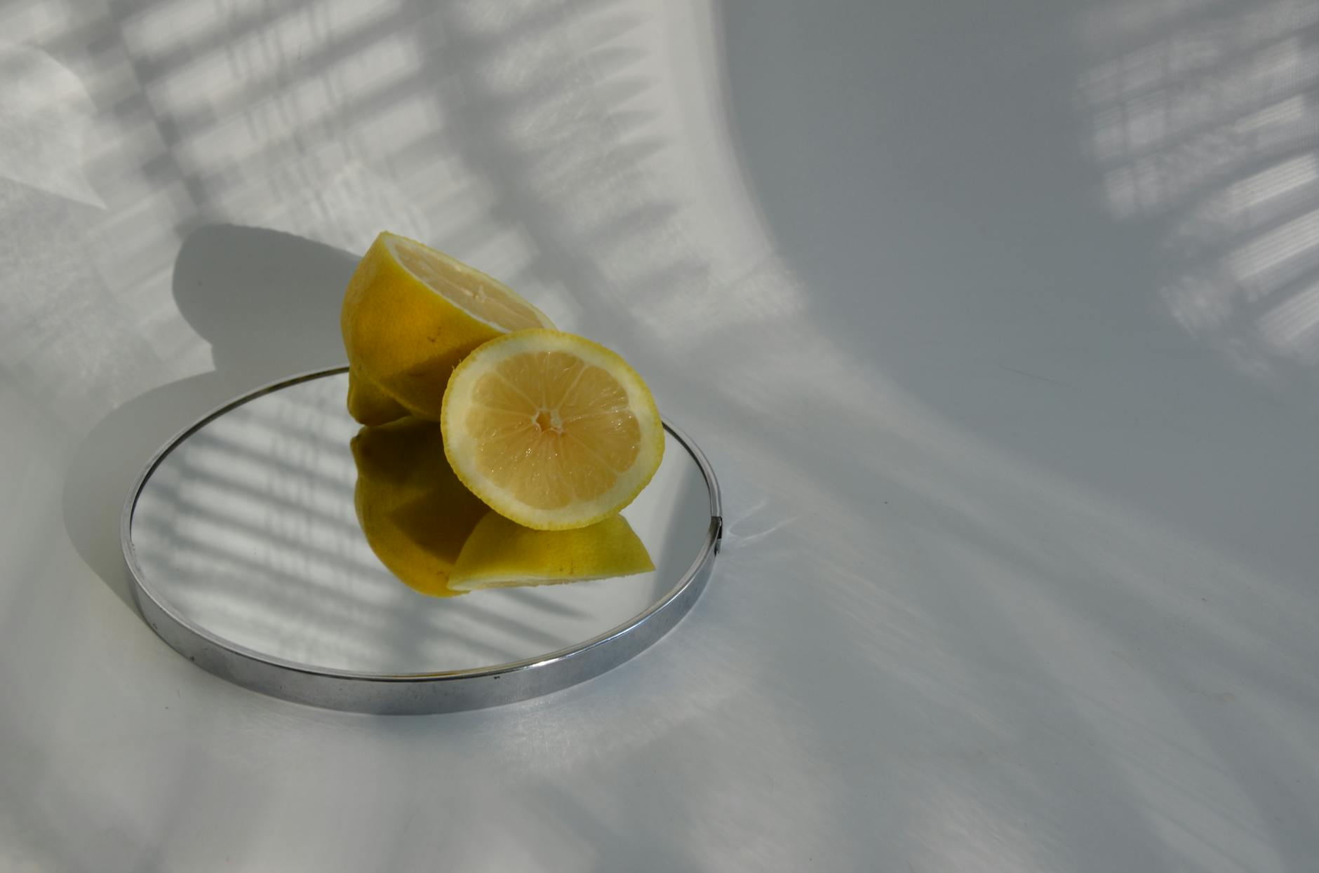 Sliced lemons on a reflective surface casting shadows, symbolizing how stress fractures our connection to sensory pleasure.