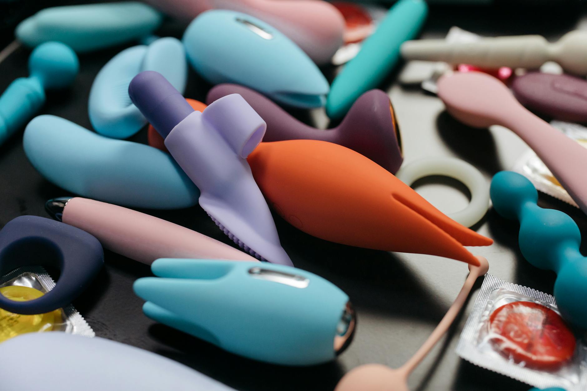 Woman holding blue and pink silicone vibrators thoughtfully