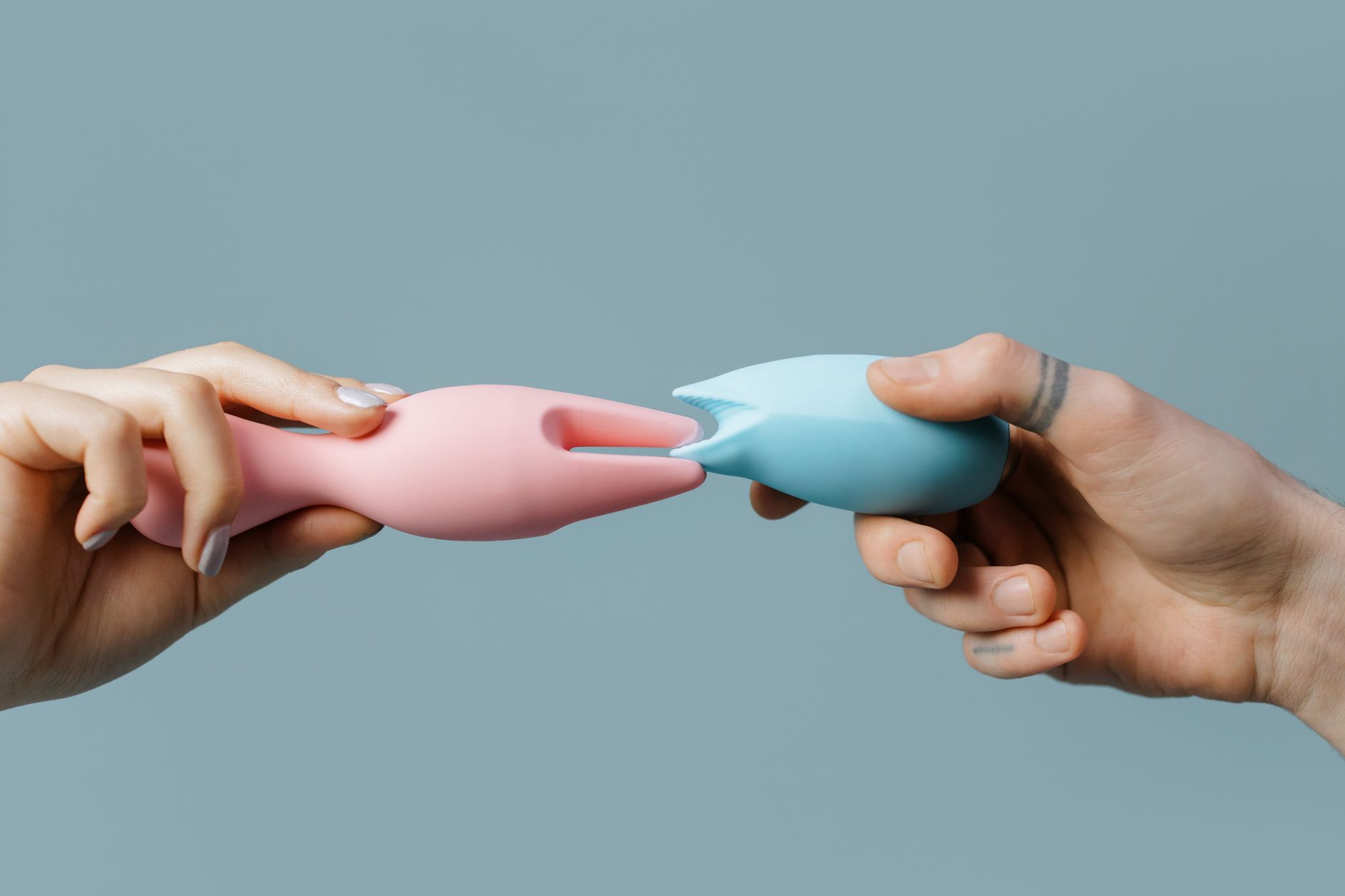 Hands holding pastel-colored silicone toys for intimate self-discovery