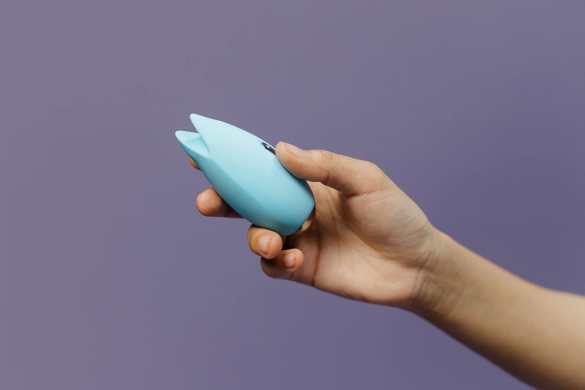 A person holding a blue silicone vibrator, promoting self-care and sexual wellness after hormonal changes.