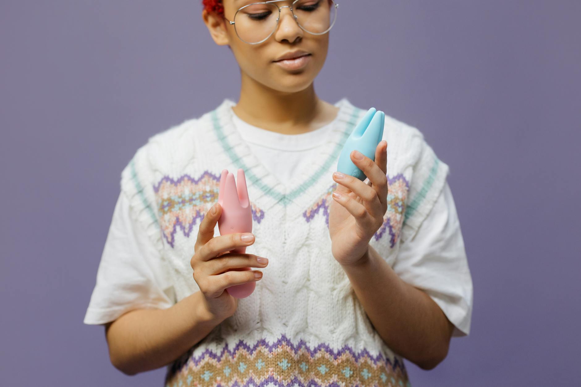 Woman holding silicone clitoral vibrators thoughtfully, representing mindful intimate pleasure.